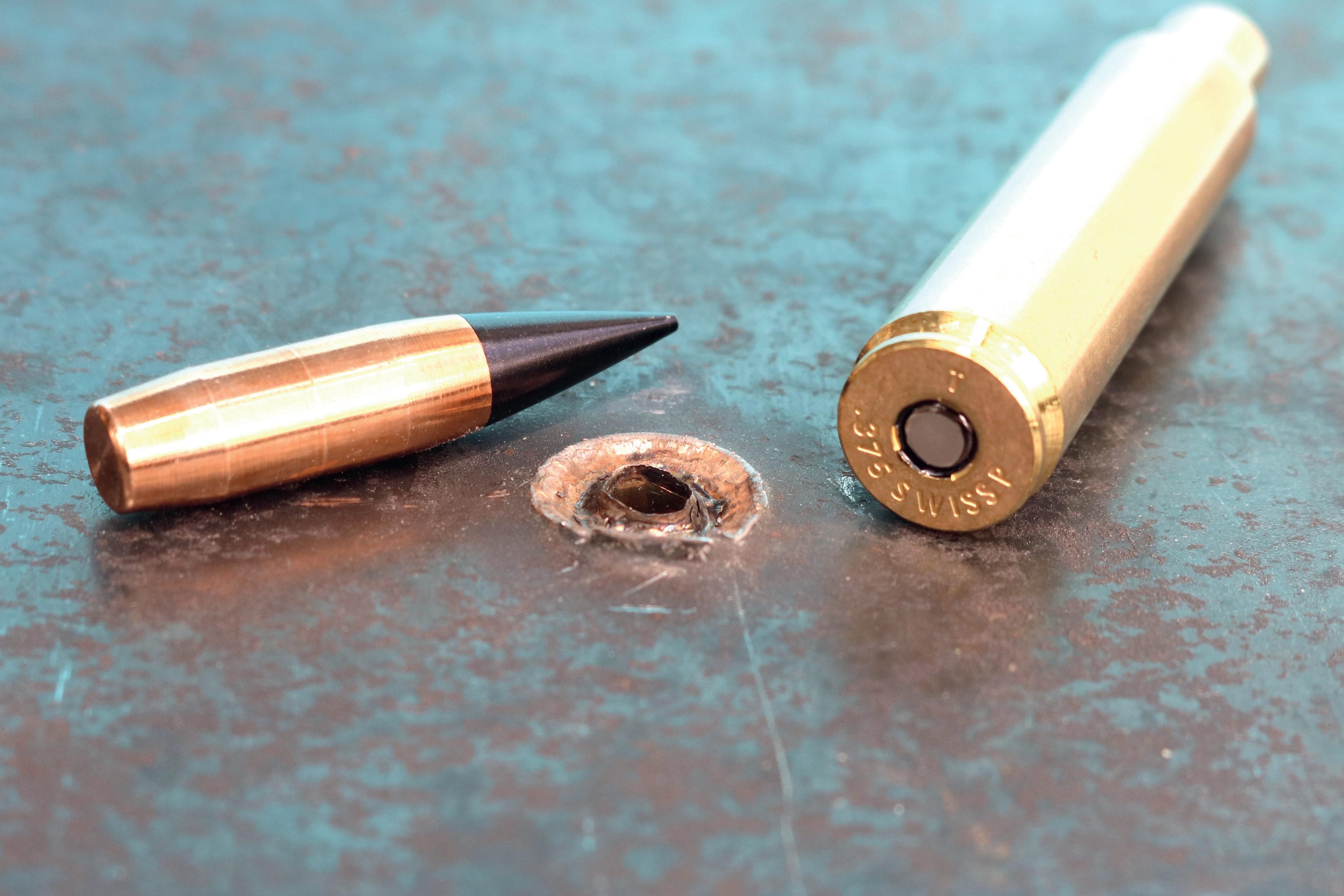 Le nouveau .375 SWISS P AP sur une plaque d’acier de blindage traversée. La pointe noire du nouveau type de projectile est bien visible.
