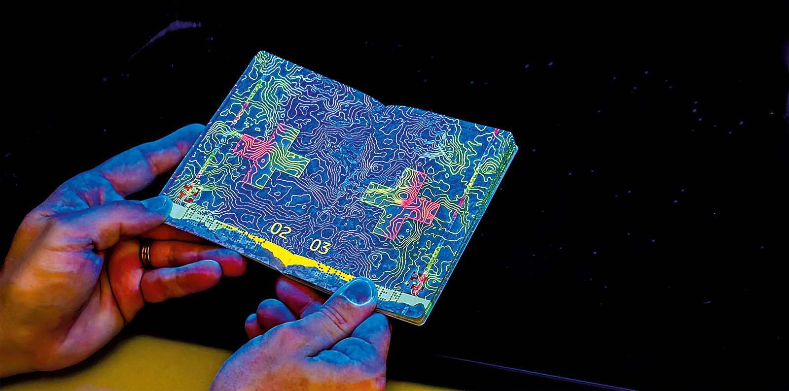 Un passeport suisse authentique présente de magnifiques reflets colorés sous la lumière UV d’un appareil de contrôle des documents.