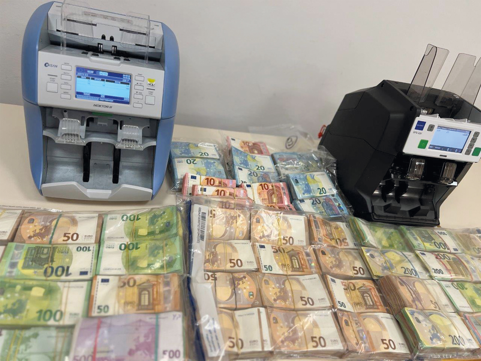 Des appareils tels que le Glory GFS-220 (à droite sur la photo) permettent de compter, de trier et d’authentifier les billets de banque en un clin d’œil, mais aussi d’enregistrer leurs numéros d’identification.