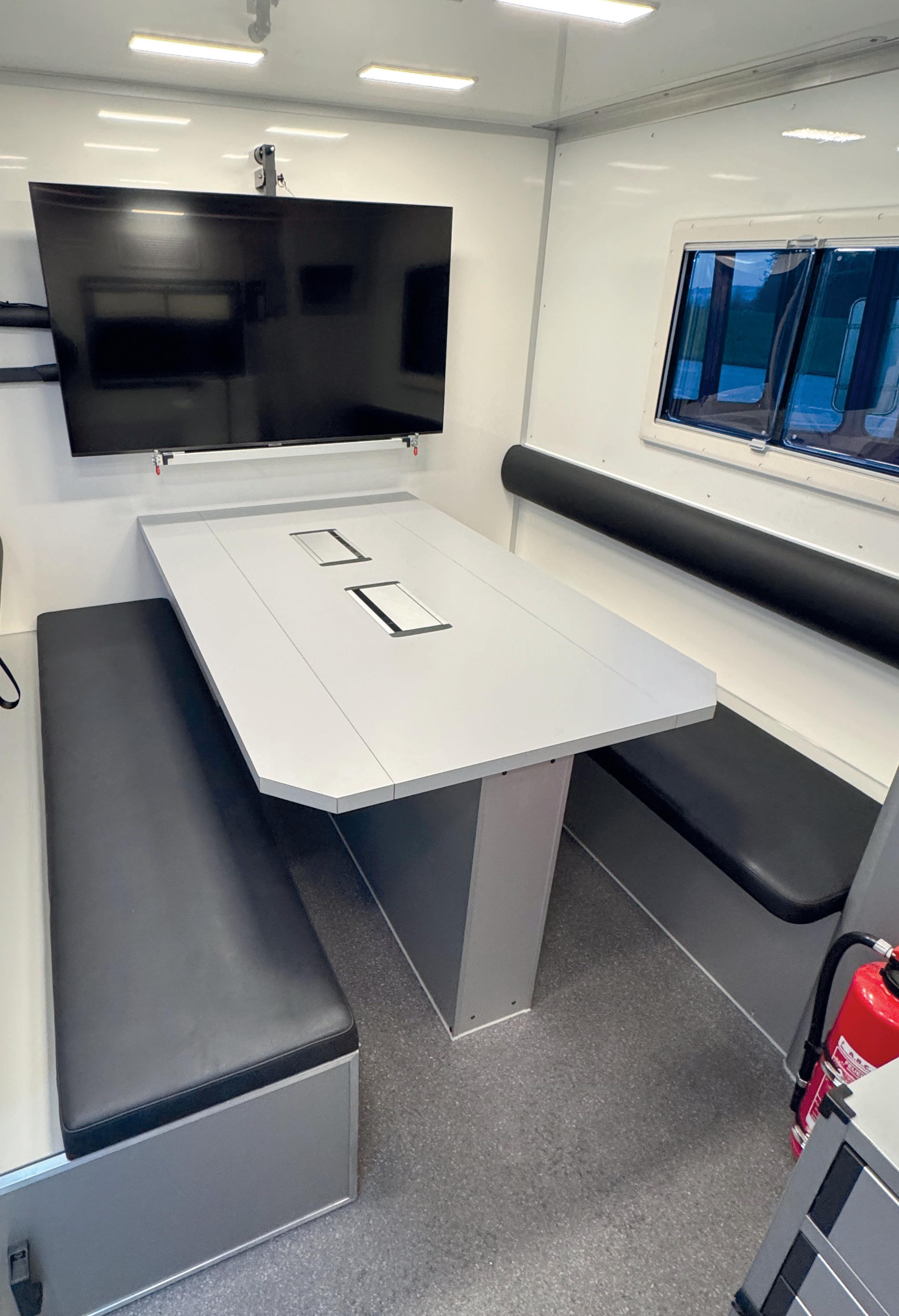 Blick in den Besprechungsraum mit zwei Sitzbänken und einem flexibel nutzbaren Tisch.